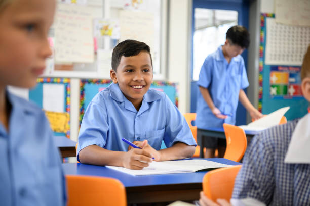 School boy wearing blue shirt listening in class with cheerful expression