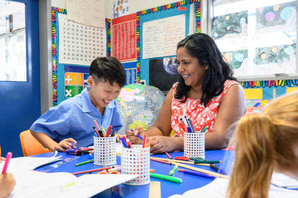 istock Aboriginal school teacher smiling towards young Asian boy working in classroom 904531330