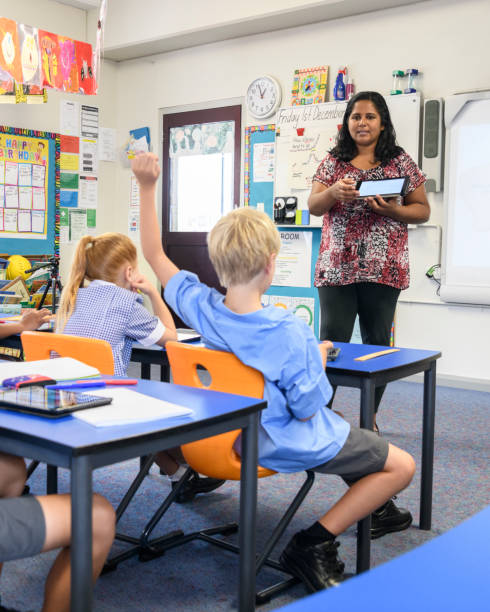 aboriginal teacher in classroom with digital tablet and young boy with arm raised - 1599 imagens e fotografias de stock