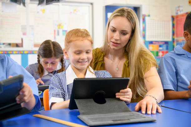 istock Teacher helping young girl using digital tablet in classroom 904531400