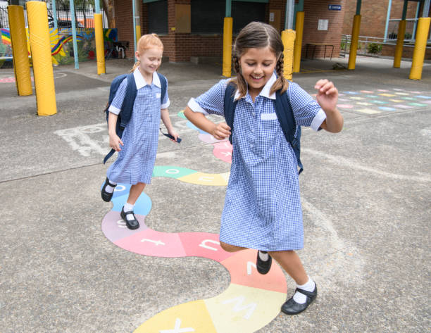 Two young girls in uniform playing in schoolyard