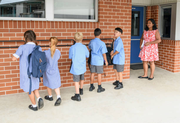 Schoolchildren running back to school and female teacher waiting isolated on white background