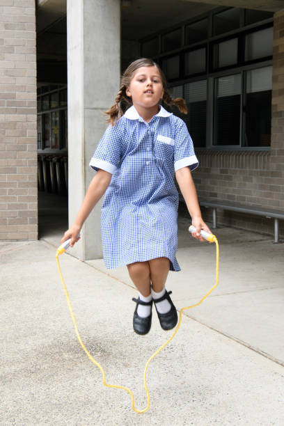 escola menina usando vestido usando pulando corda no playground - full length one person action australian culture - fotografias e filmes do acervo