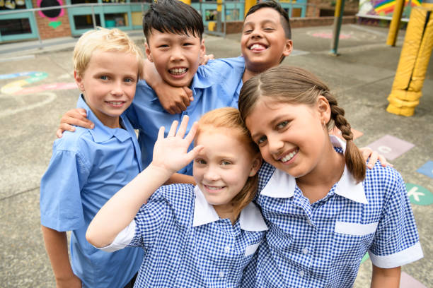 Five school friends posing for candid photo in playground Two girls and three boys wearing school uniform smiling towards camera australian culture photos stock pictures, royalty-free photos & images