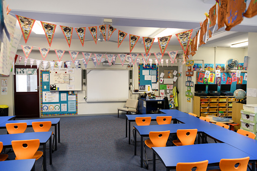 School desks and chairs in classroom with bunting hanging from ceiling