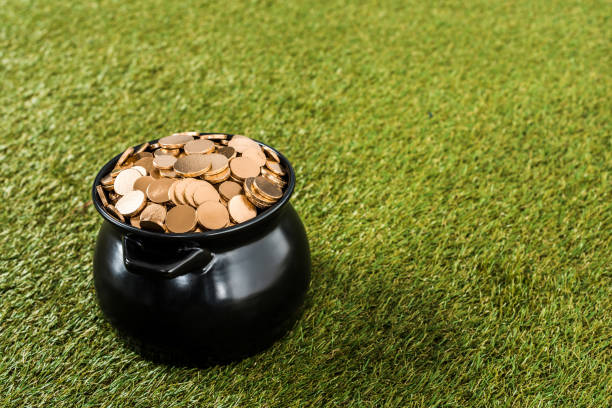 istock golden coins in pot standing on green grass 904532210