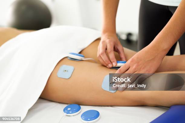 Physiotherapist Applying Electro Stimulation In Physical Therapy To A Young Woman Leg Stock Photo - Download Image Now