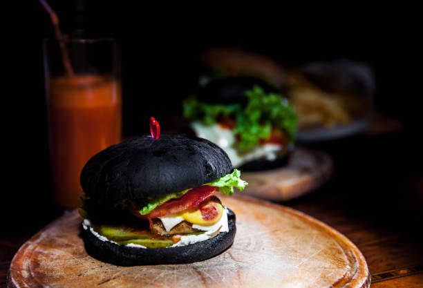 istock Modern black burger on wooden board. Toned picture 904547646