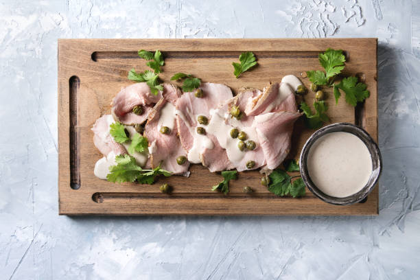 Veal with tuna sauce vitello tonnato Vitello tonnato italian dish. Thin sliced veal with tuna sauce, capers and coriander served on wooden serving board over gray texture background. Top view, space tonatiuh stock pictures, royalty-free photos & images