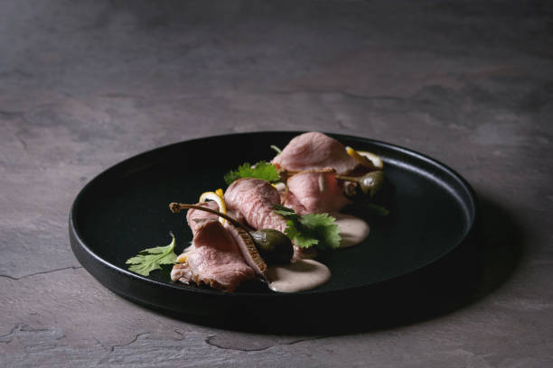 Veal with tuna sauce vitello tonnato Vitello tonnato italian dish. Thin sliced veal with tuna sauce, capers and coriander served on black plate over dark texture background. Top view, space tonatiuh stock pictures, royalty-free photos & images