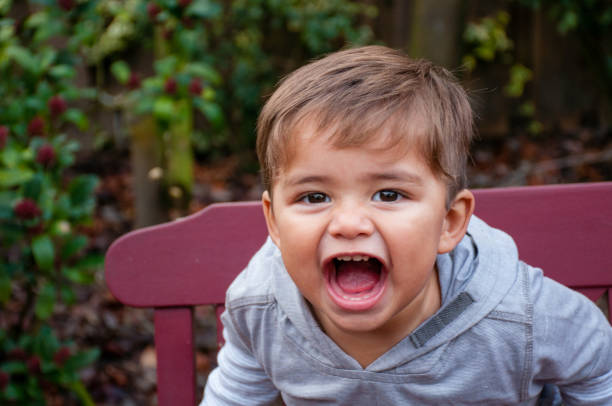 A two joyful boys sitting on green grass, laughing and enjoying their time outdoors in park. their happiness is infectious, creating lively atmosphere