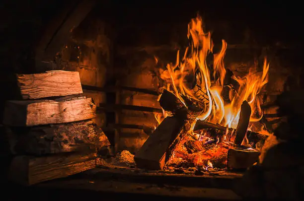 Photo of Burning fire in open fireplace with wooden fuel (firewood)