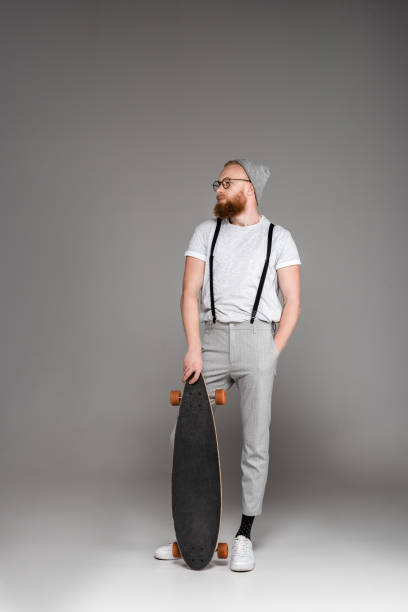 istock man standing with skateboard and looking away on grey 904554500