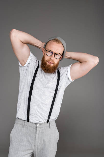 istock man in suspenders looking at camera while posing on grey 904554558