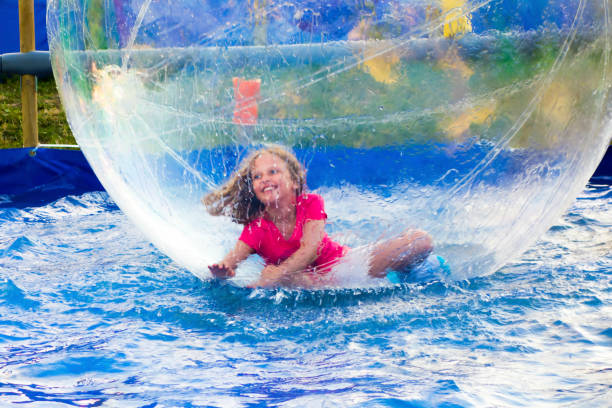 Girl in Floating Ball Young smiling girl playing inside a floating water walking ball. zorb ball stock pictures, royalty-free photos & images