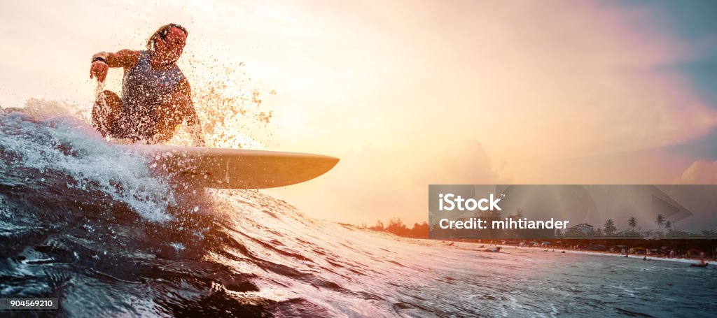 Surfer rides the ocean wave Surfer rides the ocean wave during sunset. Extreme sport and active lifestyle concept Surfing Stock Photo