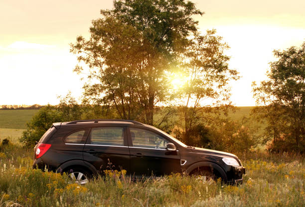 Yagodinka, Russia - May 25, 2013: Surroundings of the village Yagodinka, Rostov region. Car crossover Chevrolet Captiva against the backdrop of trees, in the rays of the setting sun.