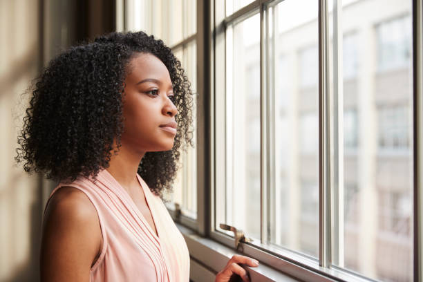 Young black businesswoman looking out of window Young black businesswoman looking out of window looking through window stock pictures, royalty-free photos & images