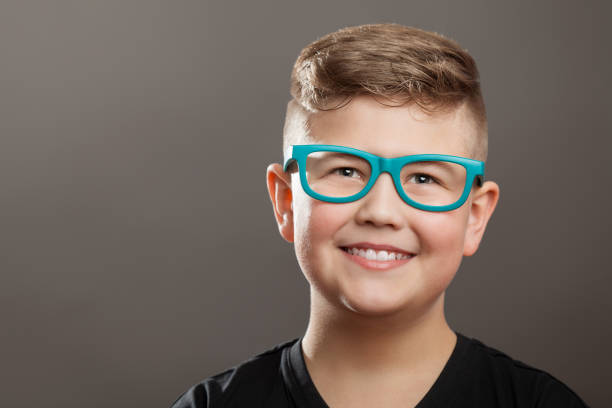 istock Smiling teenager boy with eyeglasses on grey background 904595764