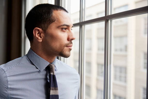 young hispanic business man looking out of window - close up businessman corporate business side view imagens e fotografias de stock