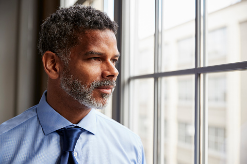 Middle aged black businessman looking out of window