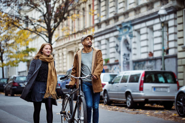 Friends walking with cycle on street during winter Friends walking with bicycle on street. Man and woman are in warm clothing. They are traveling together in city during winter. german people stock pictures, royalty-free photos & images
