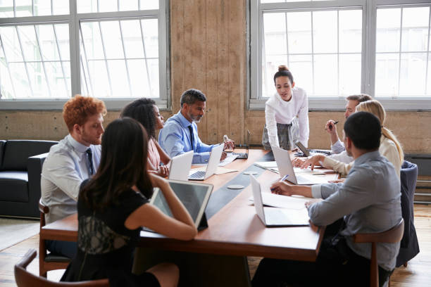 istock Female manager leans while addressing team at board meeting 904596210