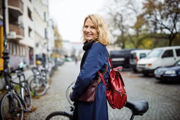 Photo of Smiling woman with bicycle in city during winter