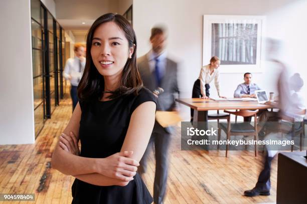 Portrait Of Young Asian Woman In A Busy Modern Workplace Stock Photo - Download Image Now