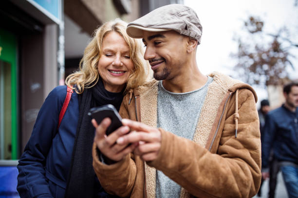 istock Smiling man showing phone to female friend in city 904599708