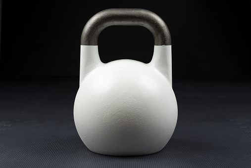 White competition kettlebell on a weight training gym floor. White competition kettlebells weigh 10kg.