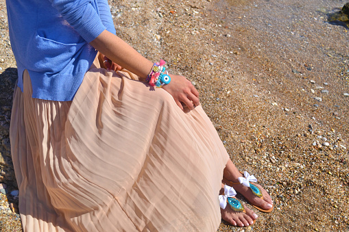 woman advertises traditional greek sandals and jewelry on beach - greek fashion accessories