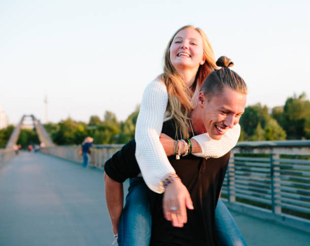 Friendship: young couple has fun with piggyback, summer in Berlin