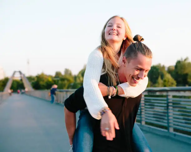 Photo of Friendship: young couple has fun with piggyback, summer in Berlin