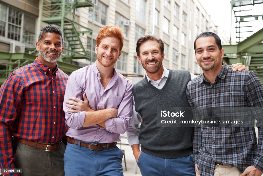 Four male coworkers smiling to camera outside Men Stock Photo