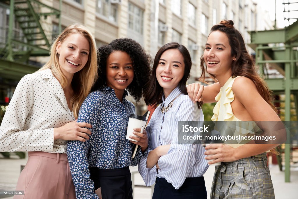 Four female coworkers smiling to camera outside Women Stock Photo