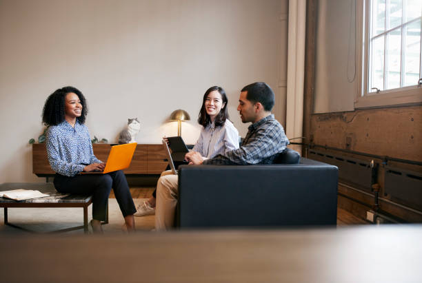 istock Smiling work colleagues using laptops at a casual meeting 904608804