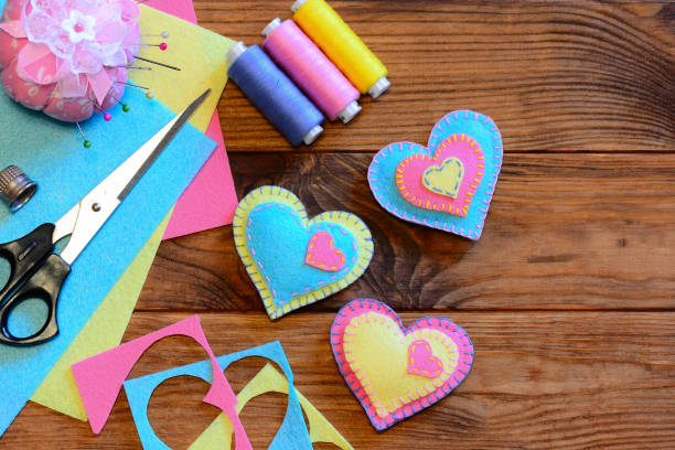 istock Valentines day ornaments idea. Felt heart ornaments, scissors, thread, pincushion, thimble, felt sheets and pieces on a wooden table. Valentines day sewing projects. Valentines romantic gifts 904620654