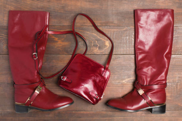istock Wine color boots and hand bag over wooden background 904621098