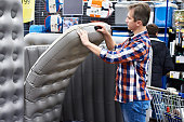 Man chooses inflatable tourist sleeping pad in sports shop