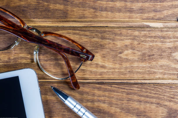 istock IPad on wood table desk with pen and eyeglasses 904626822