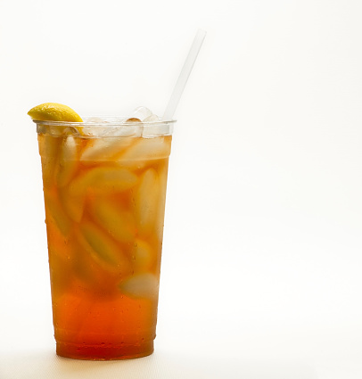 Fresh Brewed Iced Tea in a clear cup with a lemon and a straw on a white background.