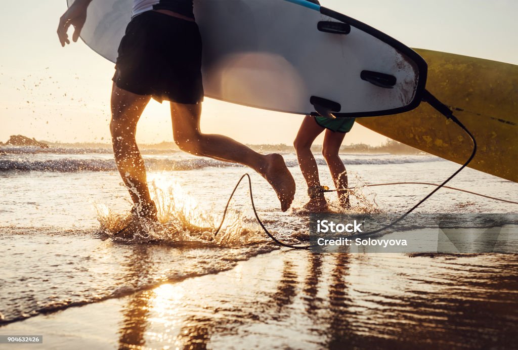 Fils et le père de surfeurs courir dans les vagues de l’océan avec longues planches. Gros plan image éclaboussures et jambes - Photo de Surf libre de droits