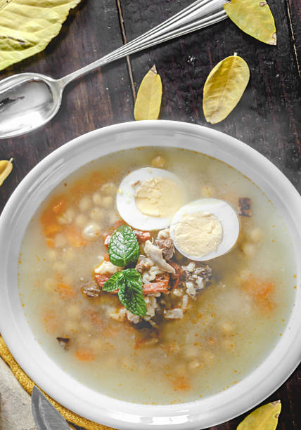 istock Healthy and warming winter soup with rice, carrot, chickpeas, chicken, ham and boiled egg over rustic wooden table background. Spanish soup (Puchero Andaluz). Top view. Winter food concept 904639074