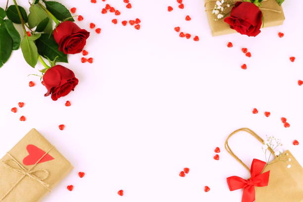 istock feminine holiday desk, table, workspace  with red roses, hearts, gift and a package on a white background. 904642704