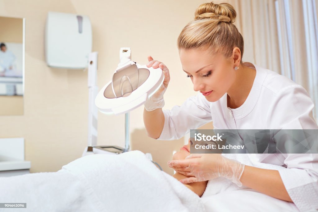 Cosmetologista é um profissional com um paciente no escritório do - Foto de stock de Esteticista royalty-free