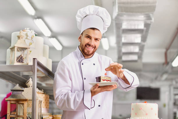 Man confectioner  with a cake in his hands in the pastr Man confectioner  with a cake in his hands in the pastry bakery. choux pastry photos stock pictures, royalty-free photos & images