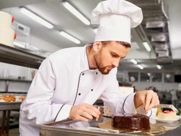 Man confectioner with a cake in his hands in the pastry Man confectioner with a cake in his hands in the pastry bakery. choux pastry photos stock pictures, royalty-free photos & images