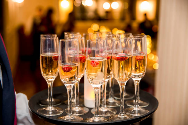 Closeup of stylish champagne flutes filled with chilled bubbly and a floating strawberries for celebrating a romantic evening together