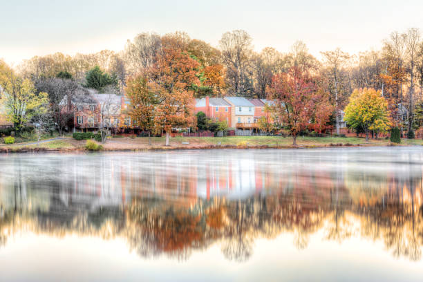 Sunrise on Braddock lake in Burke, Virginia, USA, Fairfax county with reflection of townhouses, fog, mist on water surface in autumn and orange trees Sunrise on Braddock lake in Burke, Virginia, USA, Fairfax county with reflection of townhouses, fog, mist on water surface in autumn and orange trees ashburn virginia stock pictures, royalty-free photos & images